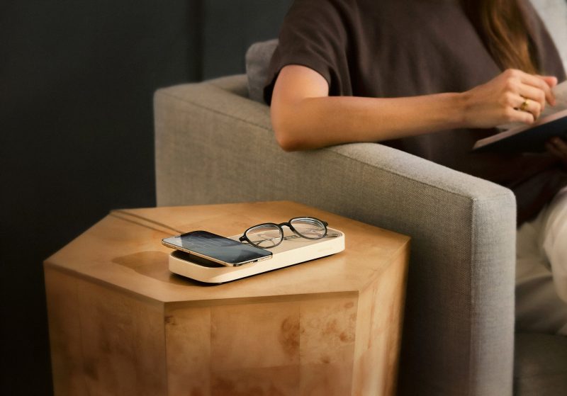 A person sitting in a chair with a phone and glasses on a table