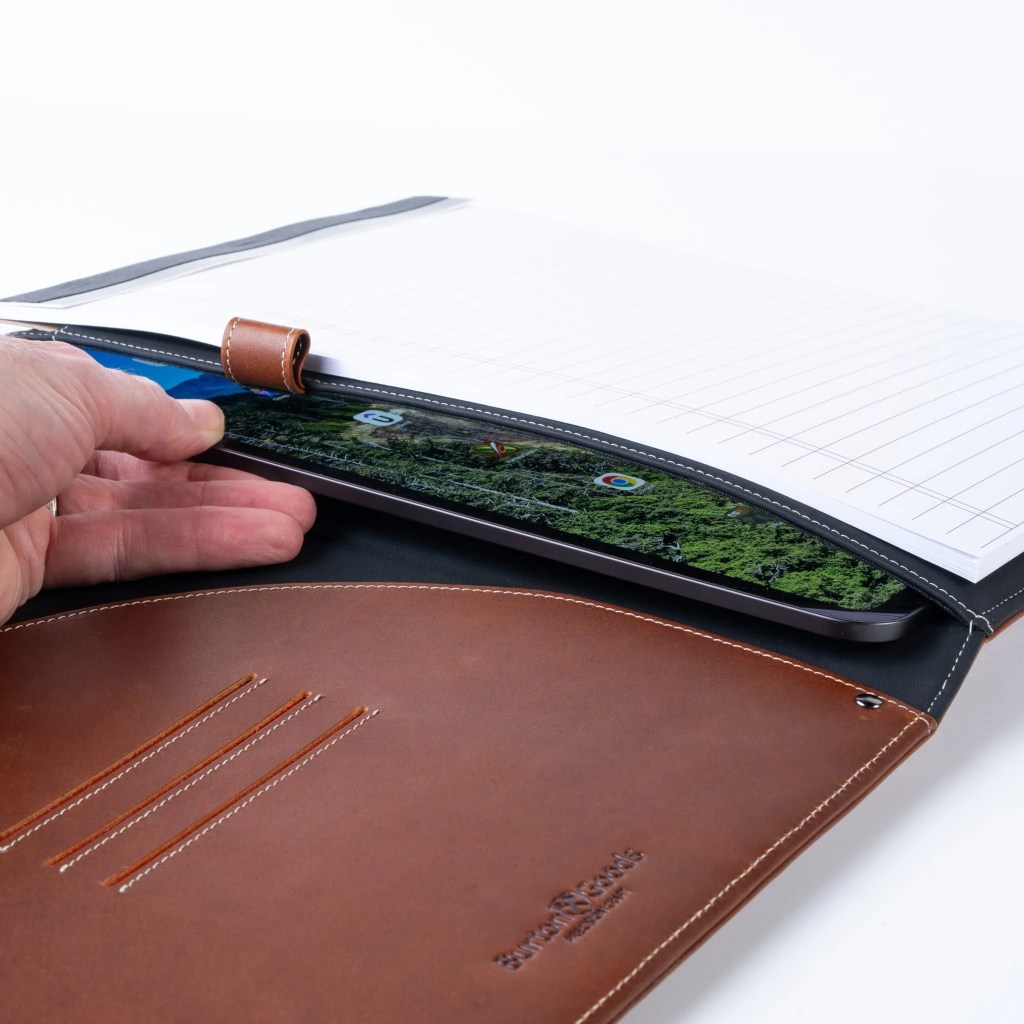 A hand holding a tablet in a leather case