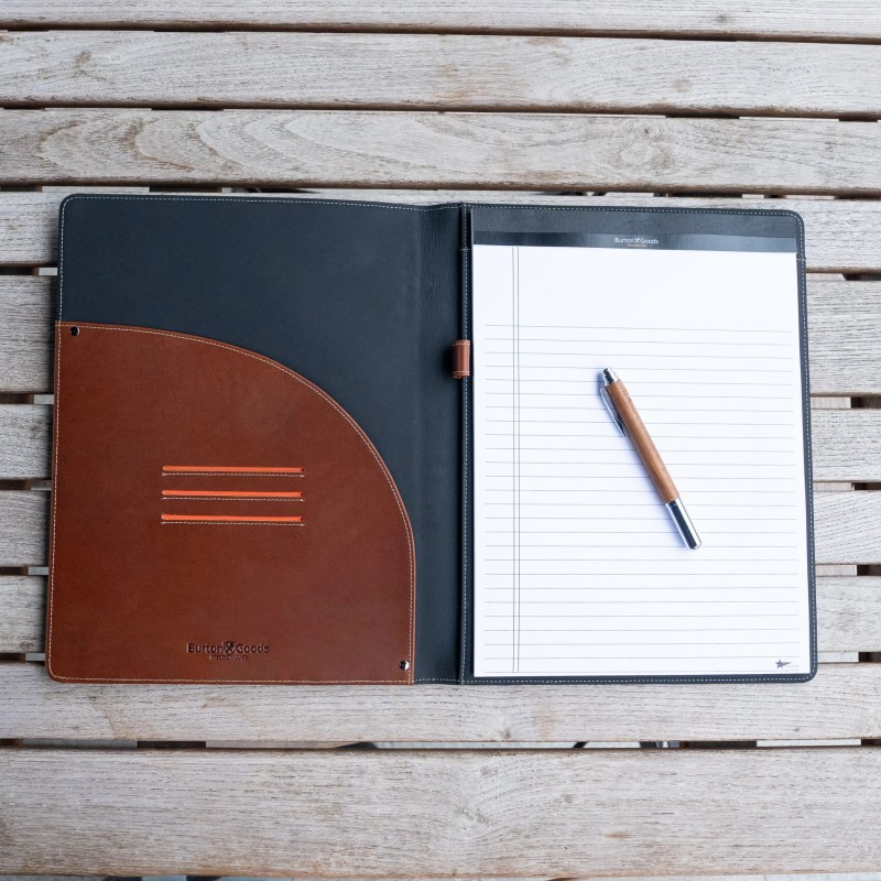 A leather folder with a pen on a wood surface
