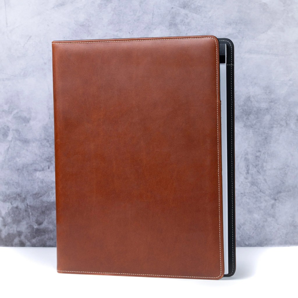 A brown leather folder with a black strap