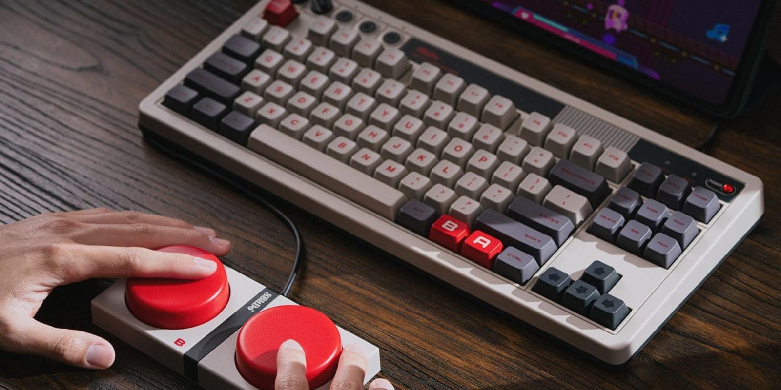 A hand holding a red and grey keyboard