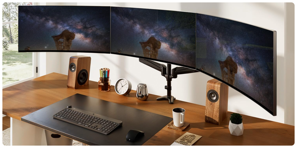 A desk with multiple monitors and speakers