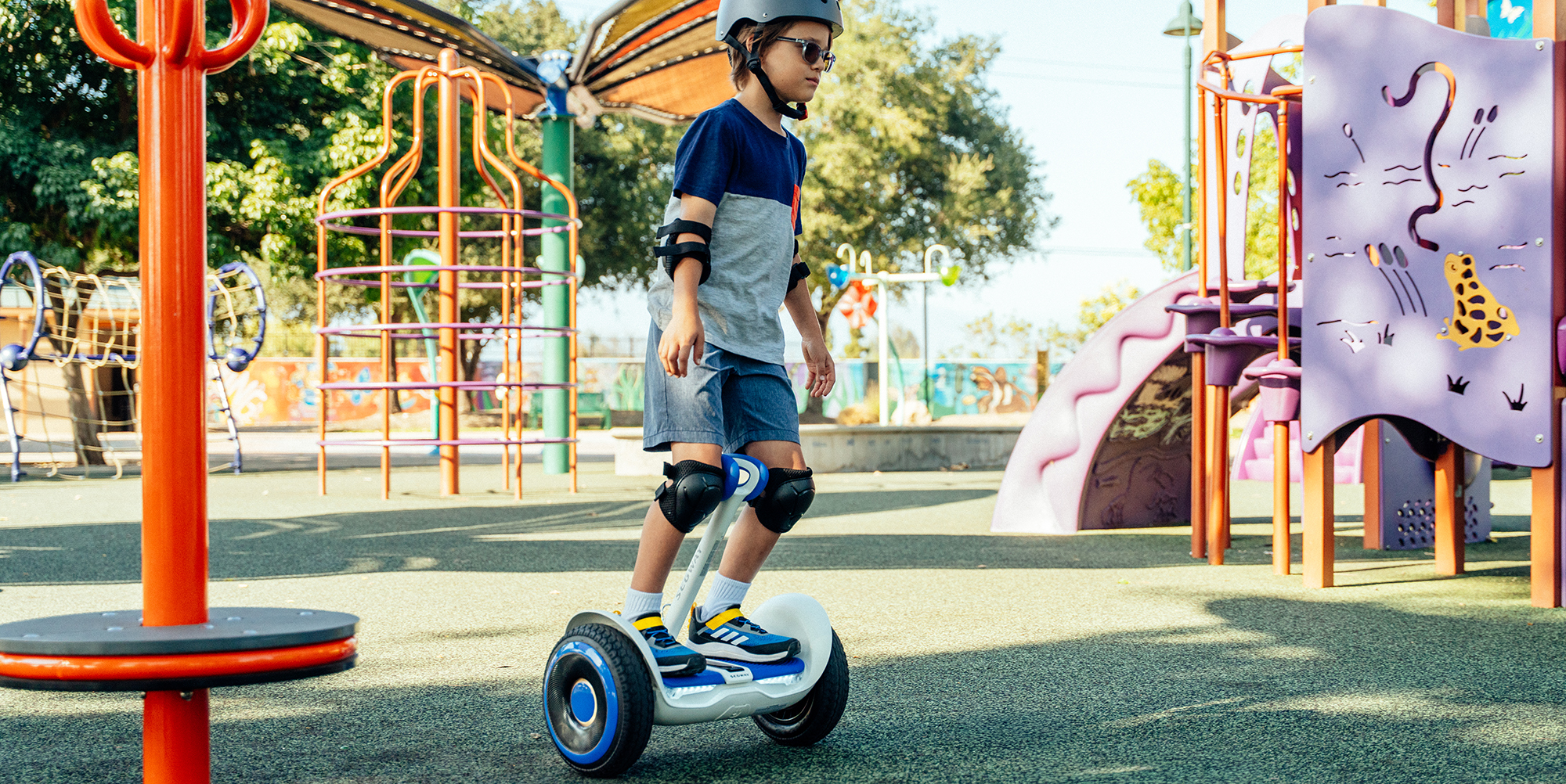 A boy wearing a helmet and knee pads riding a hoverboard