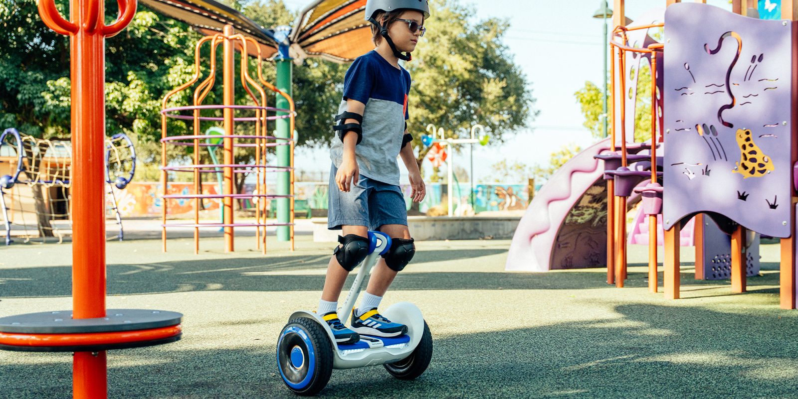 A boy wearing a helmet and knee pads riding a hoverboard