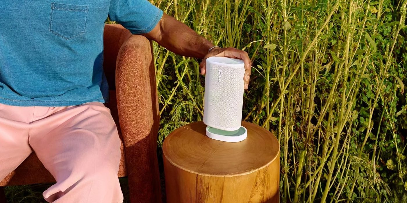 A person sitting in a chair holding a white speaker