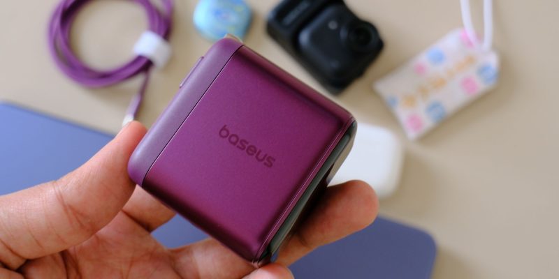 A hand holding a purple square device