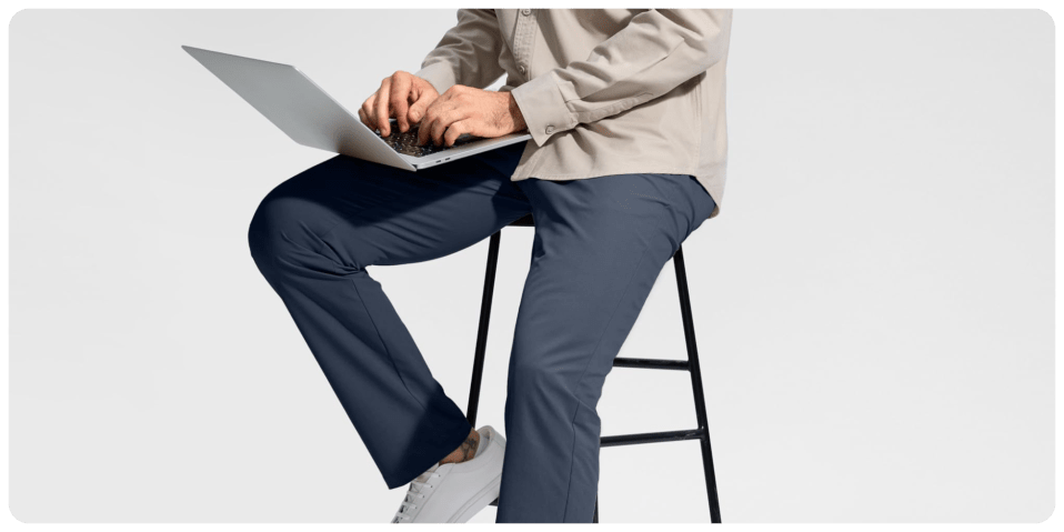 A person sitting on a stool using a laptop