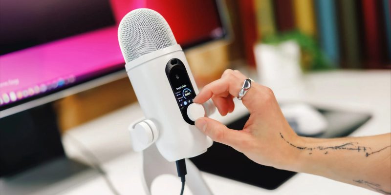 A hand turning a white microphone