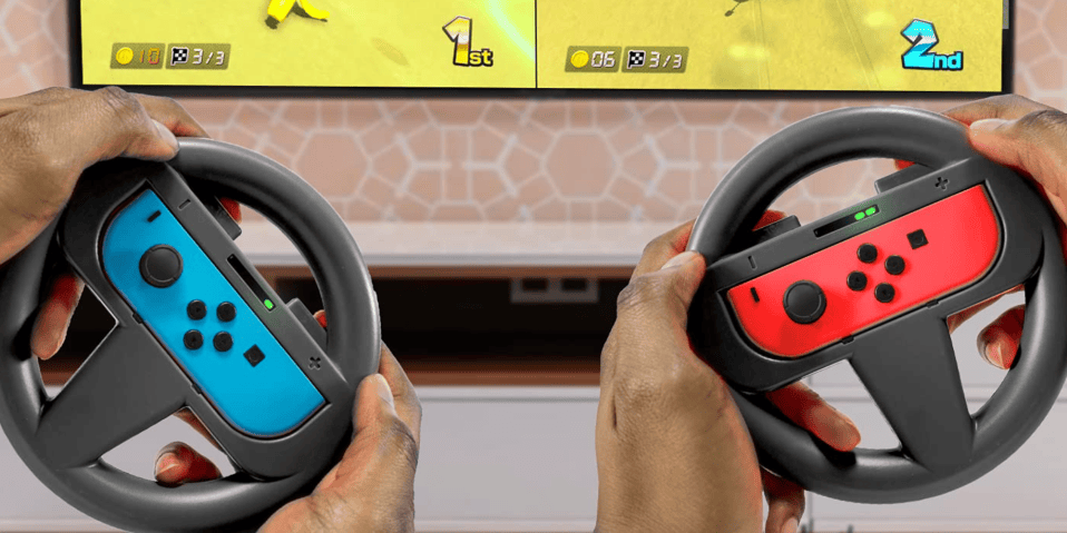 Hands holding steering wheels in front of a television