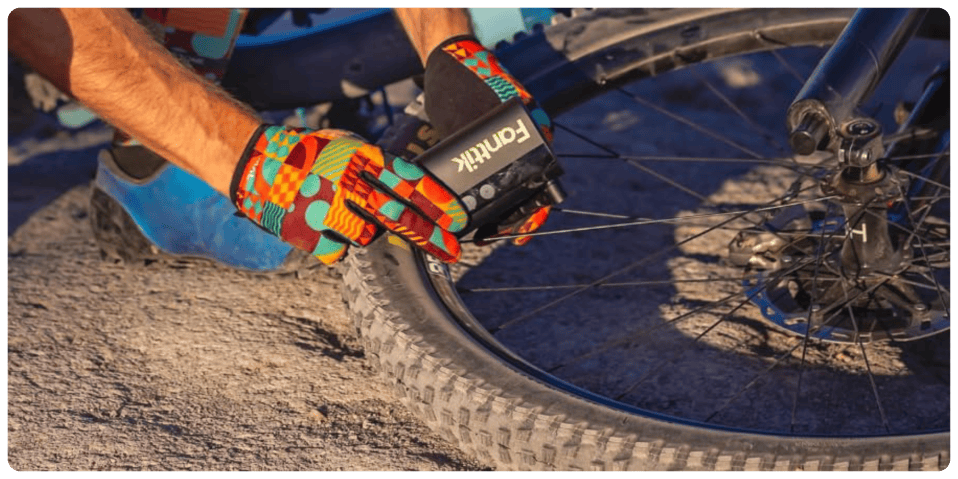 A person wearing gloves and holding a bicycle tire