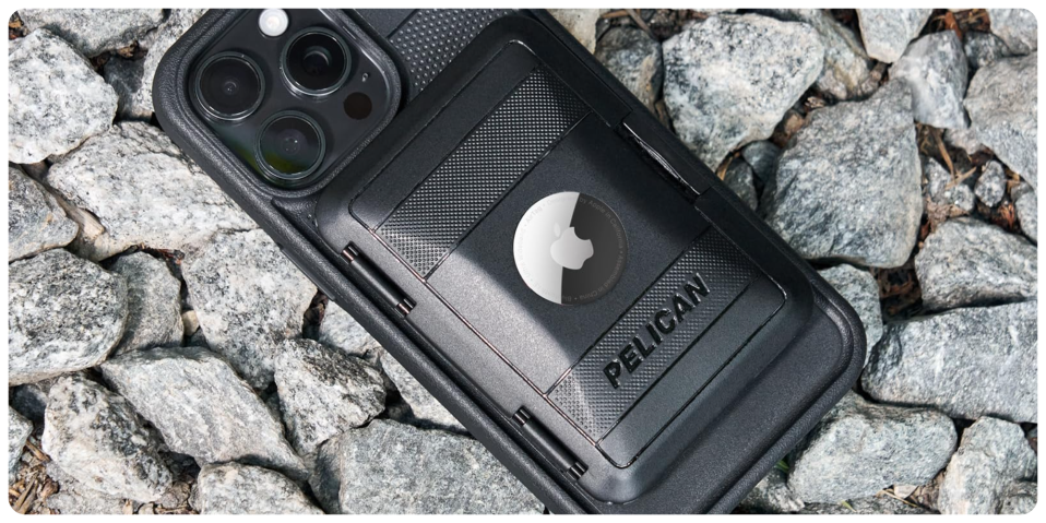 A black cell phone with a camera and a case on rocks