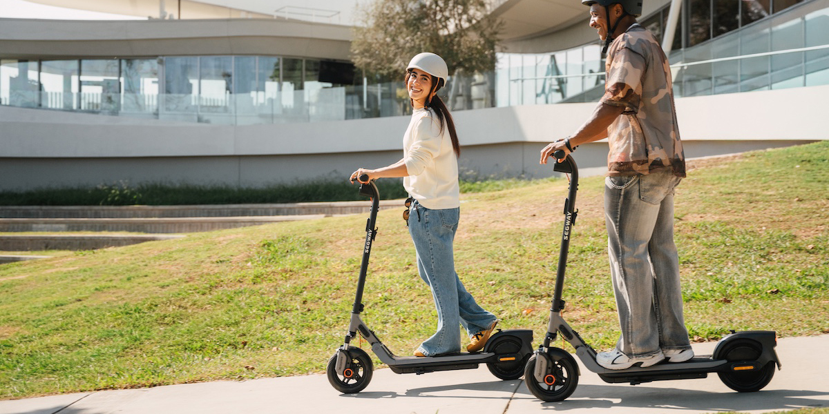 A man and woman riding scooters