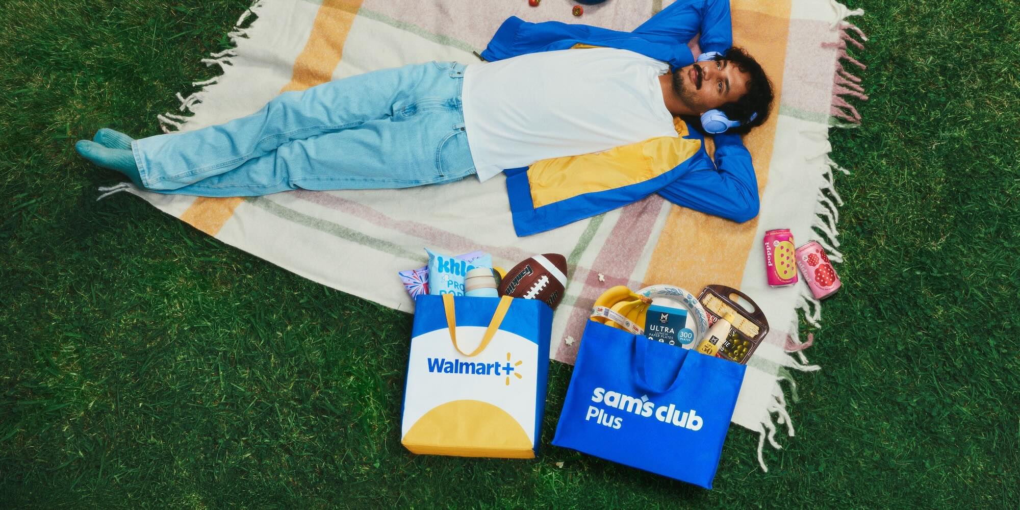 A man lying on a blanket with a bag of food and a football